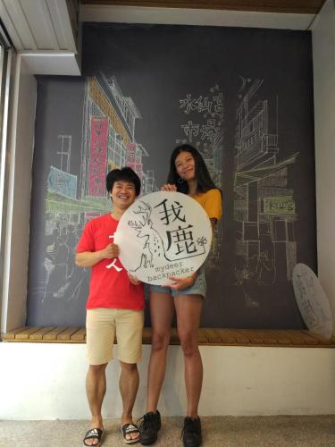 two people are holding a sign with writing on it at mydeer backpacker in Tainan
