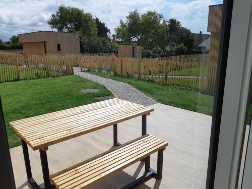 a wooden bench sitting on a patio with a yard at ETABLISSEMENT CHEZ JULES in Ambleteuse