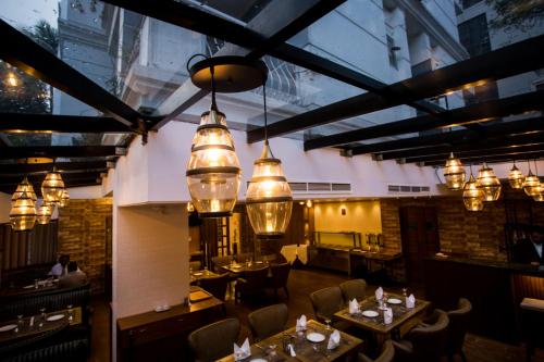 a restaurant with tables and chairs and chandeliers at Shinepukur Suites in Dhaka