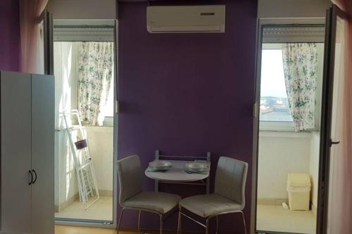 stół i krzesła w pokoju z fioletową ścianą w obiekcie Apartment KIKI, 7th floor, with a sea view, free WiFI, for 2 persons w mieście Zadar