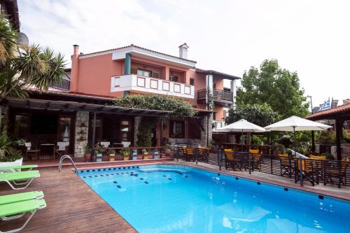 a swimming pool in front of a building with a house at Ammon Garden Hotel in Pefkochori