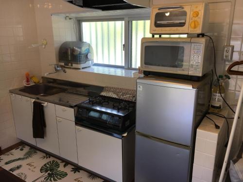 eine kleine Küche mit einem Herd und einer Mikrowelle in der Unterkunft STAY IN ALOHA in Tokashiki