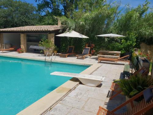 una piscina con tumbonas y sombrillas en Mas provençal à proximité du Pont Du Gard, en Sernhac