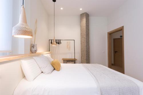 - une chambre avec un lit blanc et des oreillers blancs dans l'établissement GETARIA APARTAMENTUAK - Balentziaga, à Getaria