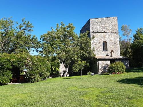 an old stone building in a field with trees at Antico Podere Vitiano - Luxury country house in Castel Viscardo