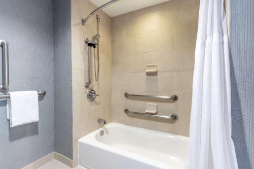 a bathroom with a tub and a white shower curtain at Hyatt Place Salt Lake City Airport in Salt Lake City