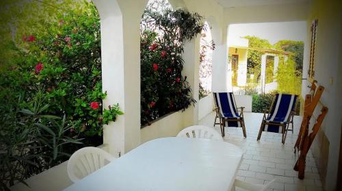 Appartamento con giardino في لامبيدوسا: طاولة بيضاء وكراسي على شرفة مع الزهور