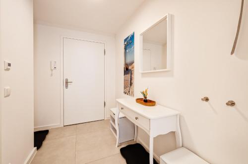 uma casa de banho branca com um lavatório e um espelho em FeWo Prora - Abendrot em Binz