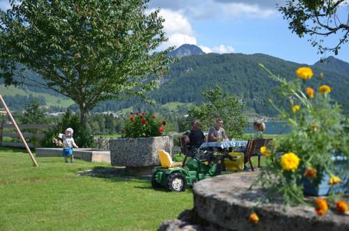 a group of people sitting at a table in a garden at Kaiserwinkl Apartments Daxer in Walchsee
