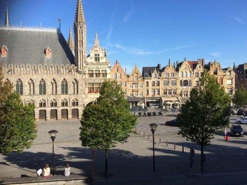 un grand bâtiment avec une tour d'horloge dans une ville dans l'établissement Hotel New Regina, à Ypres