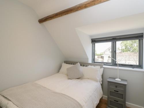 a white bedroom with a bed and a window at Kingfisher, 2 The Old Stables in Witney