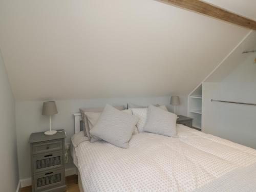 a white bedroom with a bed with white sheets and pillows at Swallows, 1 The Old Stables in Witney