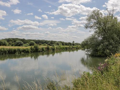 a river with trees and clouds in the sky at Swallows, 1 The Old Stables in Witney