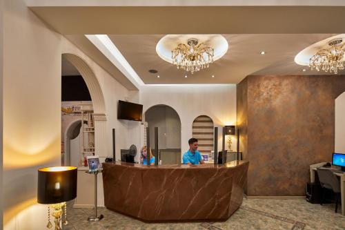 a man sitting at a reception desk in a lobby at Blue Sea Hotel in Kamari