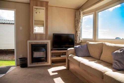 a living room with a couch and a television at Devon Cliffs Holiday Home in Exmouth
