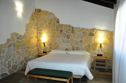 1 dormitorio con cama blanca y pared de piedra en Hostal Restaurante Villa de Brihuega en Brihuega