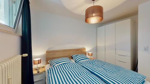 a bedroom with a bed with blue and white stripes at Strandnahe, moderne Ferienwohnung auf Wangerooge, Seeluft 34 in Wangerooge