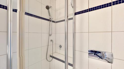 a shower in a bathroom with white tiles at Seeluft 34 - Wangerooge in Wangerooge