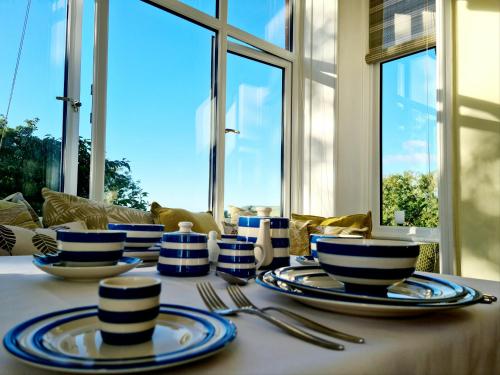 uma mesa com pratos e talheres azuis e brancos em Boscastle House em Boscastle