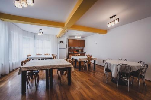 een kamer met tafels en stoelen en een keuken bij La Pădure Pensiune-Restaurant in Novaci-Străini