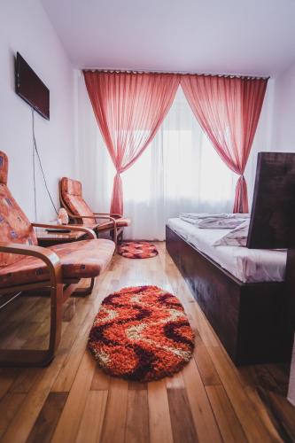 a bedroom with a bed and a chair and a rug at La Pădure Pensiune-Restaurant in Novaci-Străini