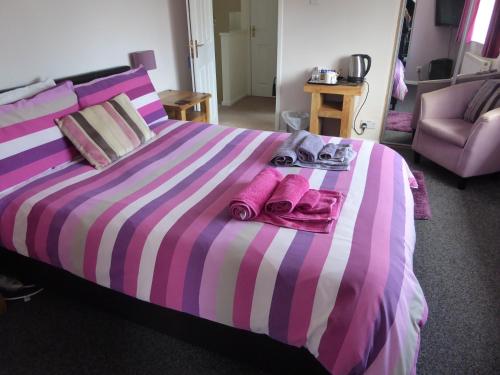 a large bed with pink and purple striped sheets at Mayfields Guest House in Wokingham