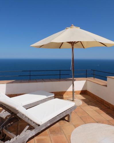 a patio with an umbrella and two chairs and a table at El Far Hotel Restaurant in Llafranc