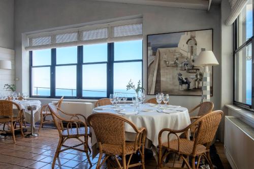 a dining room with a table and chairs and windows at El Far Hotel Restaurant in Llafranc