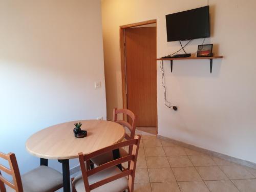 a room with a table and chairs and a television at Apartmani Dalmatinka in Metajna