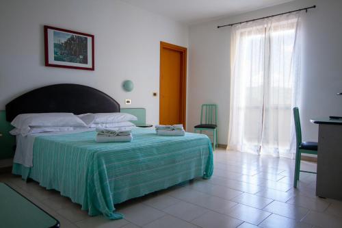 a bedroom with a bed with a green blanket and a window at Falcon Hotel in SantʼAgata Feltria