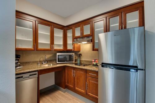 a kitchen with wooden cabinets and a stainless steel refrigerator at Staybridge Suites Missoula by IHG in Missoula