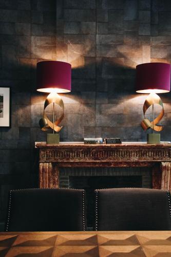 two lamps on top of a fireplace with two chairs at Hotel FRANQ in Antwerp