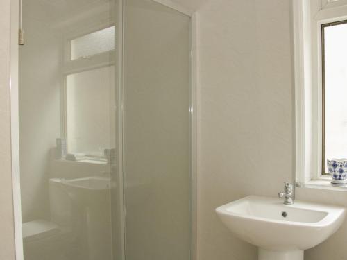 a white bathroom with a shower and a sink at Whitewater Cottage in Llangollen
