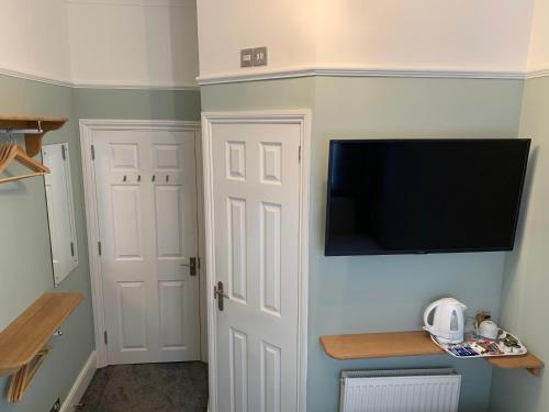 um quarto com uma televisão numa parede com uma porta em Rivendell Guest House em Southampton