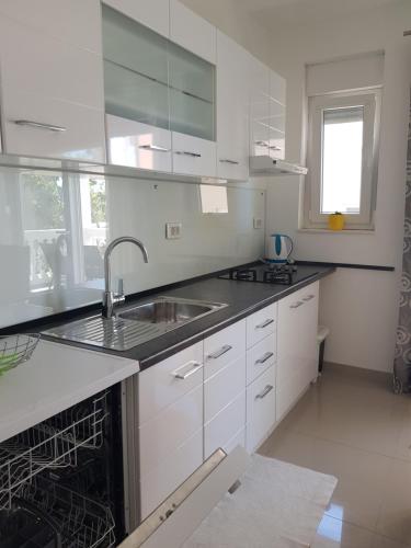a kitchen with white cabinets and a sink at Apartman Zrno in Vodice