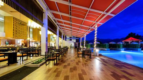 un restaurant avec une piscine, des tables et des chaises dans l'établissement Peach Blossom Resort & Pool Villa - SHA Plus, à Kata Beach