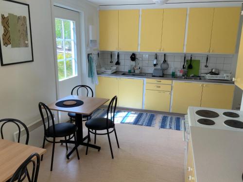 uma cozinha com armários amarelos, uma mesa e cadeiras em Evedals Vandrarhem Växjö em Växjö