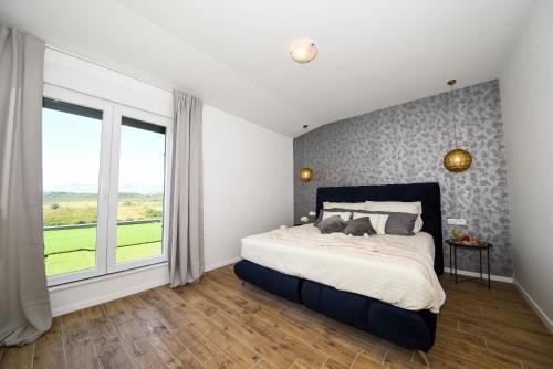 a bedroom with a bed and a large window at Vila Matak in Ražanac