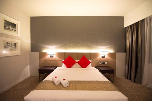 a hotel room with a large bed with red pillows at Raia Hotel & Convention Centre Alor Setar in Alor Setar