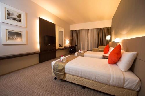 a hotel room with two beds and a television at Raia Hotel & Convention Centre Alor Setar in Alor Setar