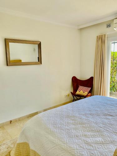 a bedroom with a bed and a mirror and a chair at LUXURY 3 BEDROOM HOUSE AT LA QUINTA GOLF COURSE OCEAN and MOUNTAIN VIEW in Benahavís