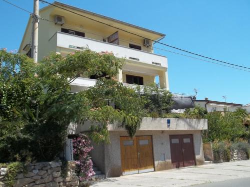 a house with two doors and flowers in front of it at Lovrić Apartments in Baška