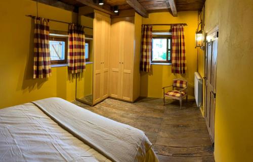 a bedroom with yellow walls and a bed and a chair at Casa Rural La Costurera in Los Espejos de la Reina