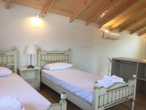 2 łóżka w pokoju z białymi ścianami i drewnianymi sufitami w obiekcie Aliki Boutique Hotel w mieście Paralia Vrachou