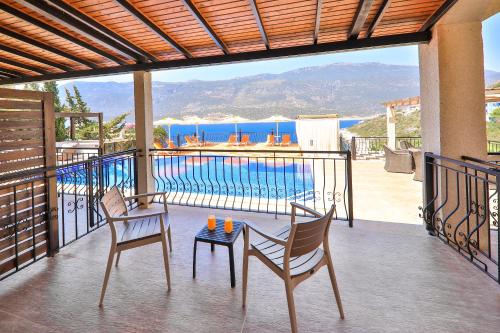 a balcony with two chairs and a table and a pool at Atalante Hotel in Kas