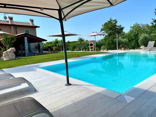 a swimming pool with an umbrella next to a house at Poggio Bardolino in Bardolino