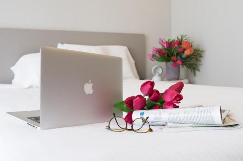 ordenador portátil en una cama con flores y vasos en Contempora Apartments - Elvezia 8 - E14, en Milán