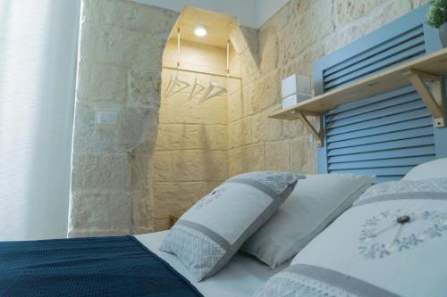 a bedroom with a bed with a stone wall at Donato Rooms in Trani
