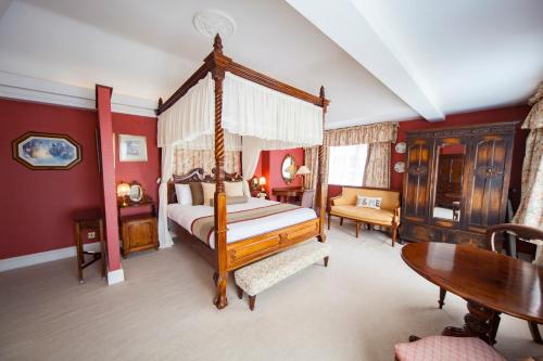 a bedroom with a canopy bed and a table at The Holt Hotel in Steeple Aston