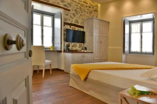 a bedroom with a bed and a desk and a television at Manolia in Hydra